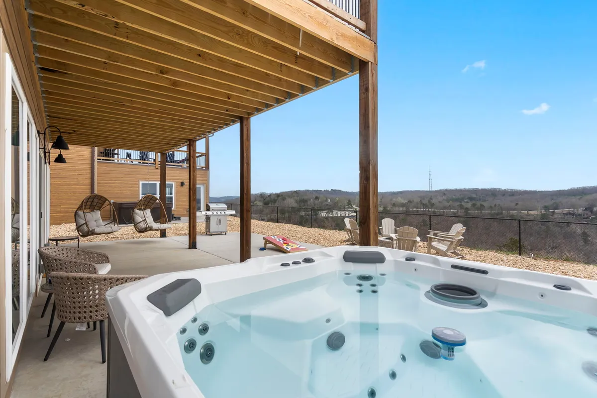 This image captures a tranquil outdoor area featuring a hot tub, inviting seating, and panoramic views of the landscape. The hot tub is positioned to look out over the surroundings, suggesting relaxation at sunset or under the stars.