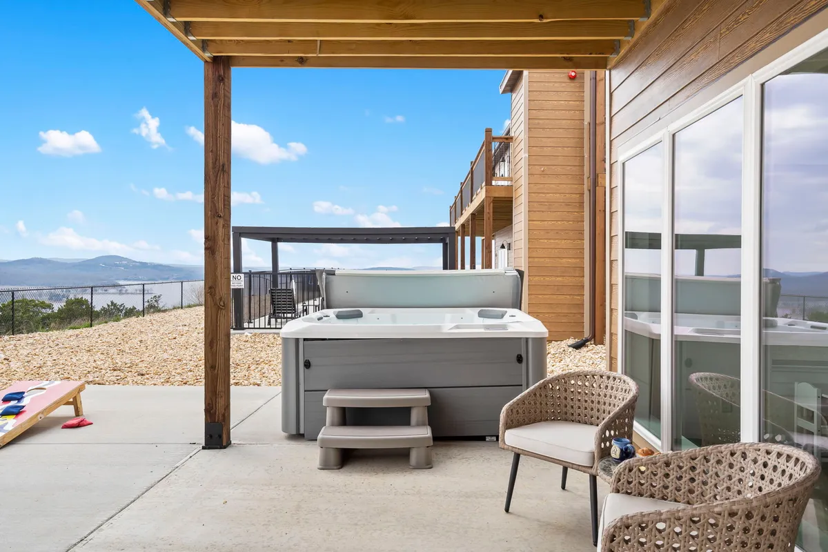 This image features a hot tub situated on an outdoor patio with comfortable seating and a stunning mountain view in the background. The setting exudes tranquility and invites visitors to relax and unwind in a natural setting.