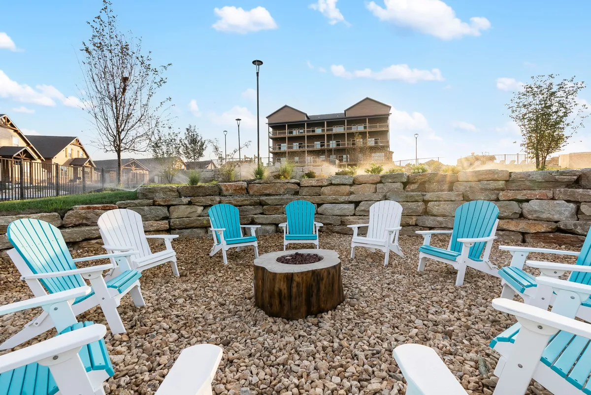 A cozy exterior gathering spot with a stone firepit surrounded by Adirondack chairs, inviting guests to unwind, roast marshmallows, and share stories under the stars. The scene exudes warmth and a sense of community.