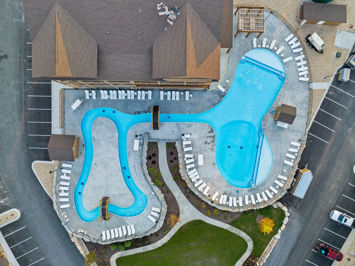 A vibrant exterior view featuring two sparkling outdoor swimming pools surrounded by poolside loungers and lush landscaping. The inviting water and ample seating suggest a perfect space for both relaxation and social gatherings.